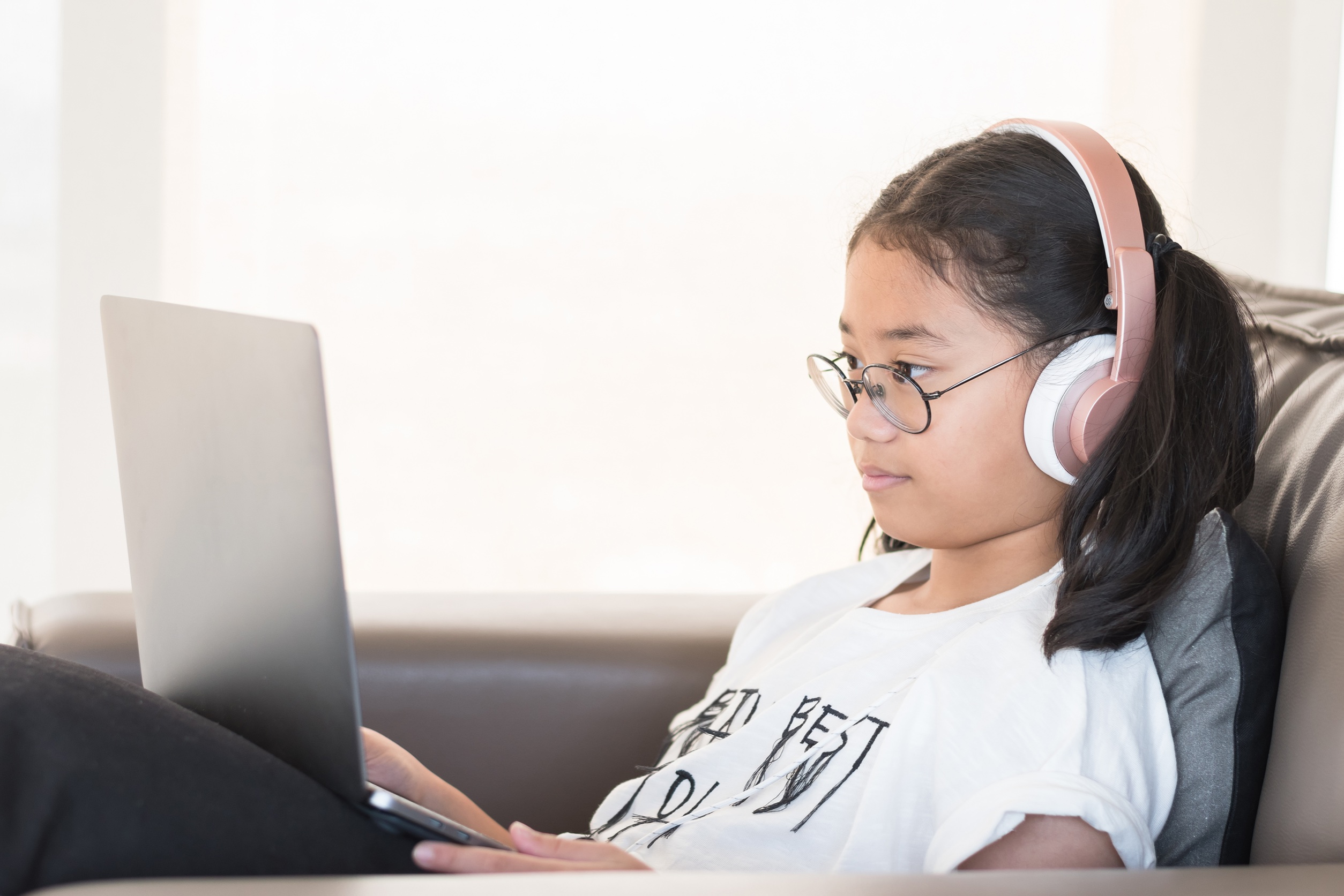 young black girl seated, listening to a lesson on her tablet while reading the screen